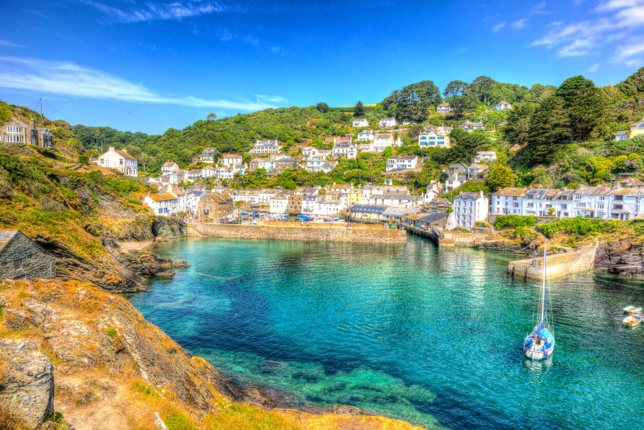 image of a village in cornwall on a sunny day, with white buildings and a crystal clear sea